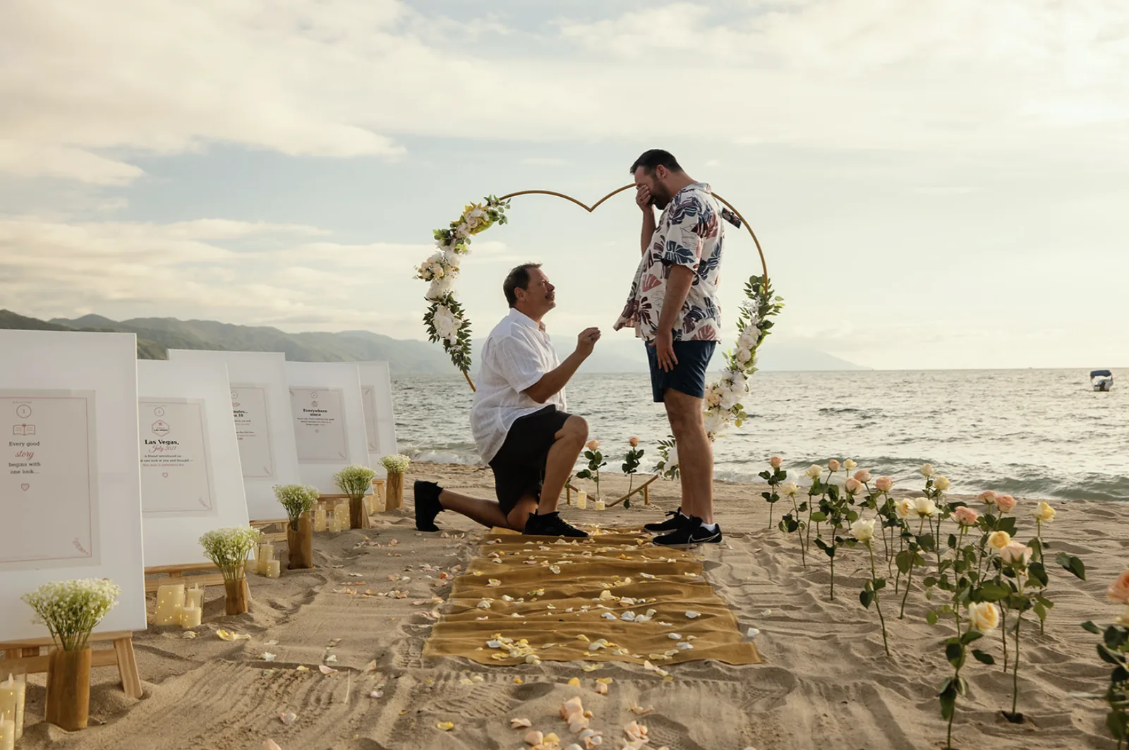 Patrick proposing to Mitch under a floral heart arch on a Puerto Vallarta beach